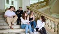 Photo of the group of students sitting on the stairs in the WUT Main Building