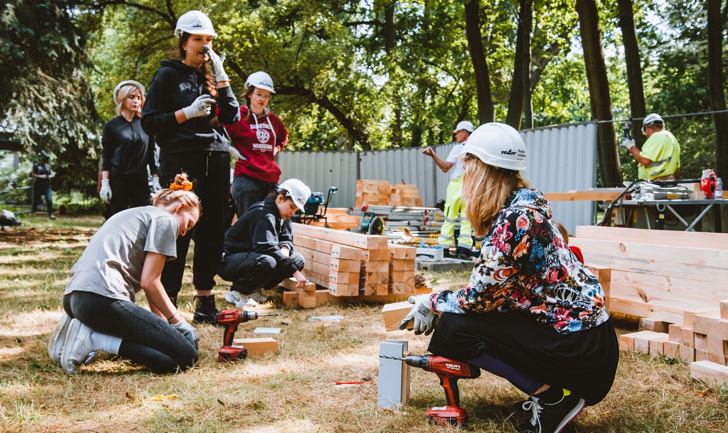 Photo of female students and builders at a construction site