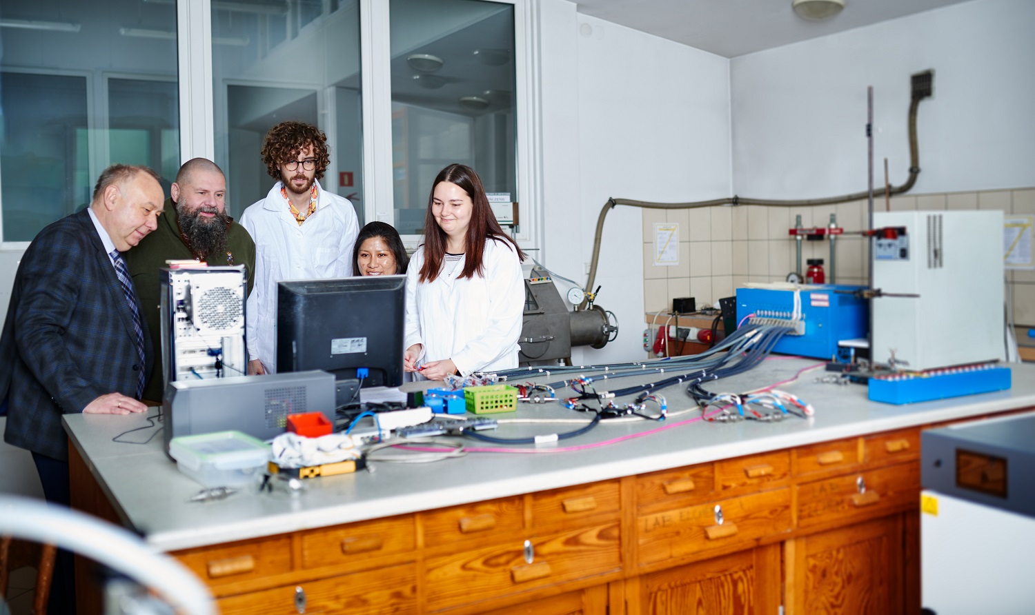 Photo of prof. Władysław Wieczorek, prof. Marek Marcinek and doctoral students who deal with battery technology at the Faculty of Chemistry. People are leaning over computer