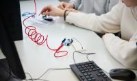 Photo of a mouse, computer, electronic device and hands in two people