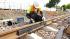 A man wearing a helmet and a reflective vest is working on the railway tracks