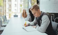 Photo of the student sitting at the table and making notes