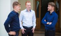 Photo of three students who are standing and talking